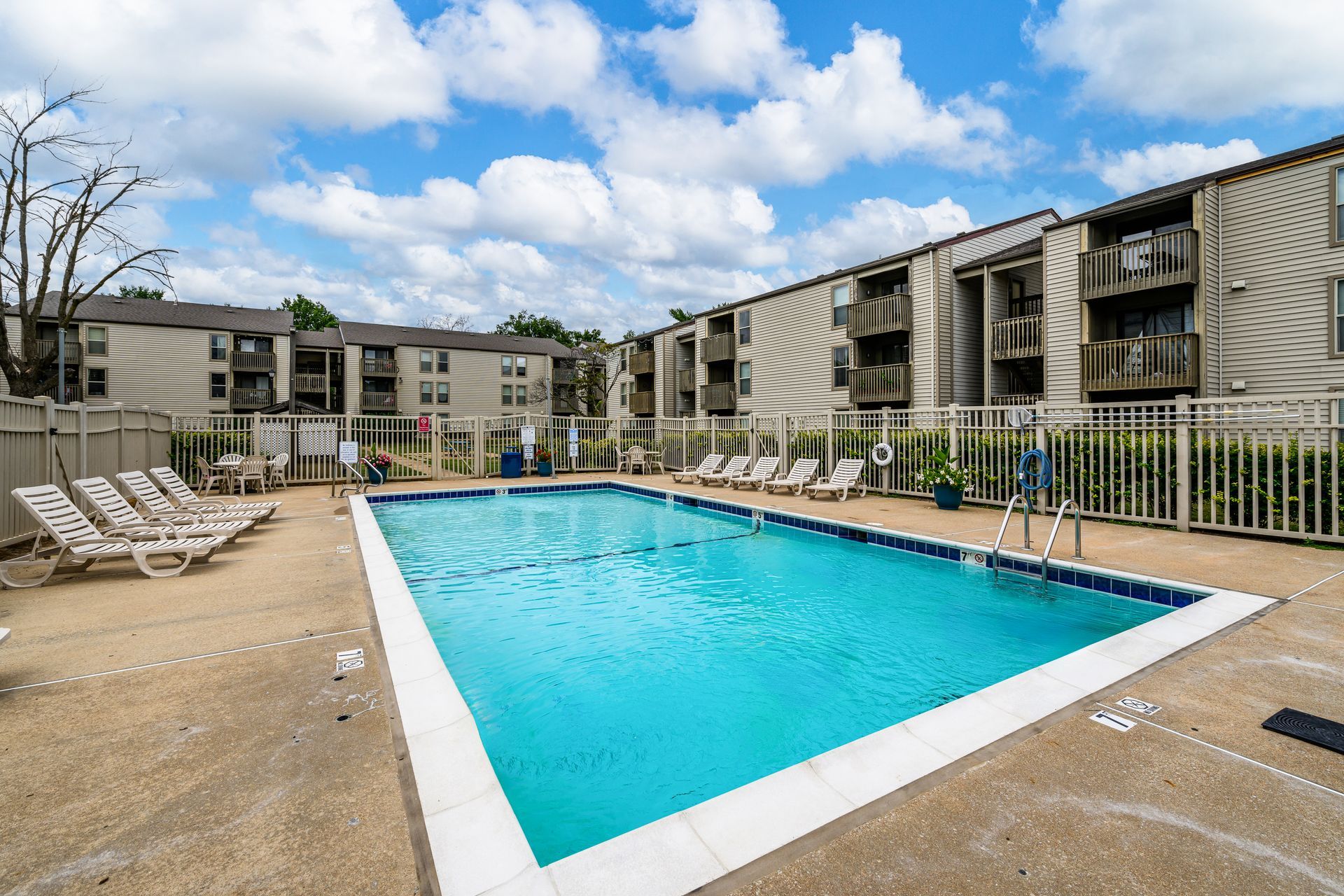 A large swimming pool surrounded by chairs in front of a building.