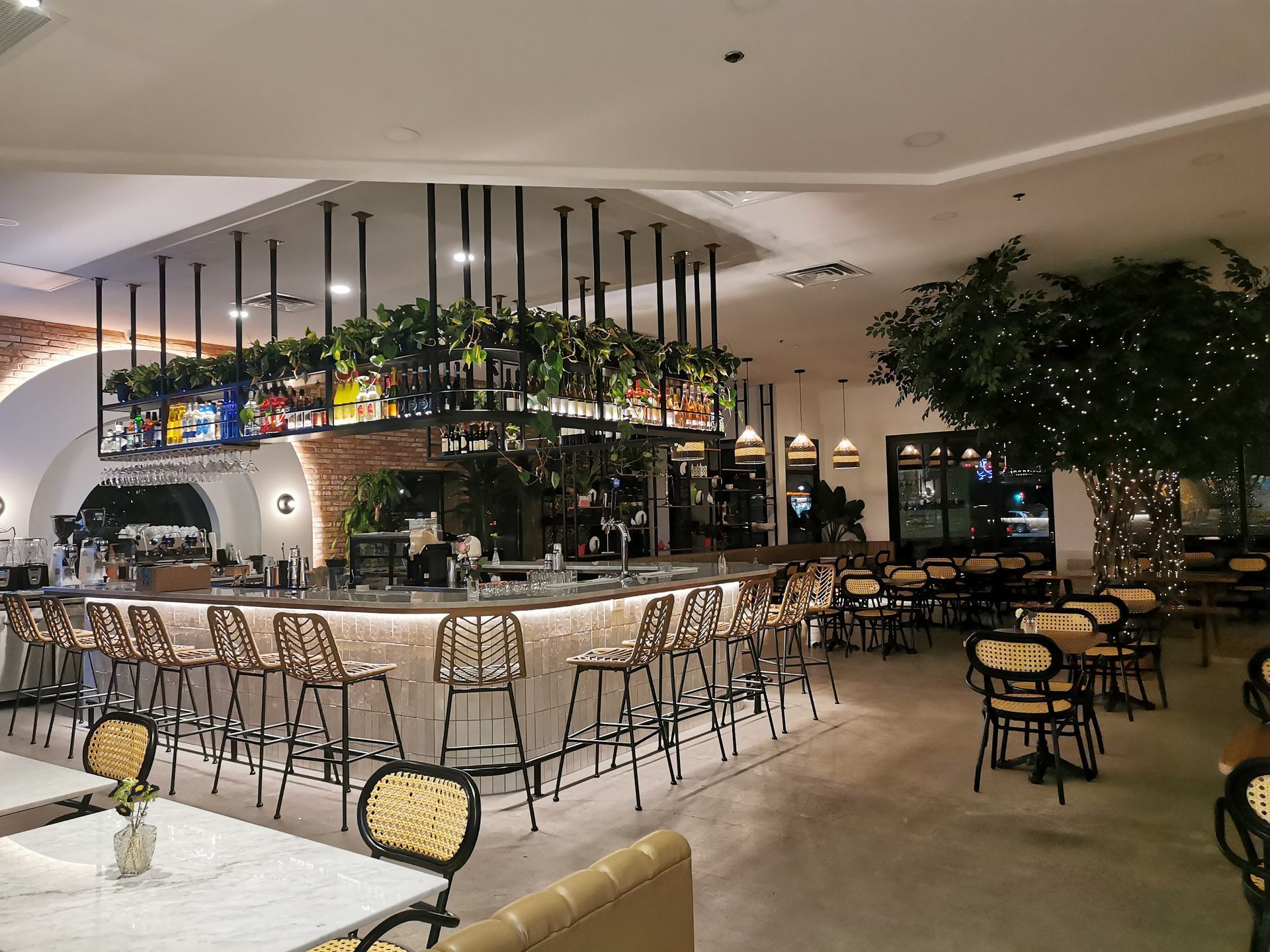 Restaurant et bar élégant en intérieur avec tables vides, tabourets et plantes suspendues