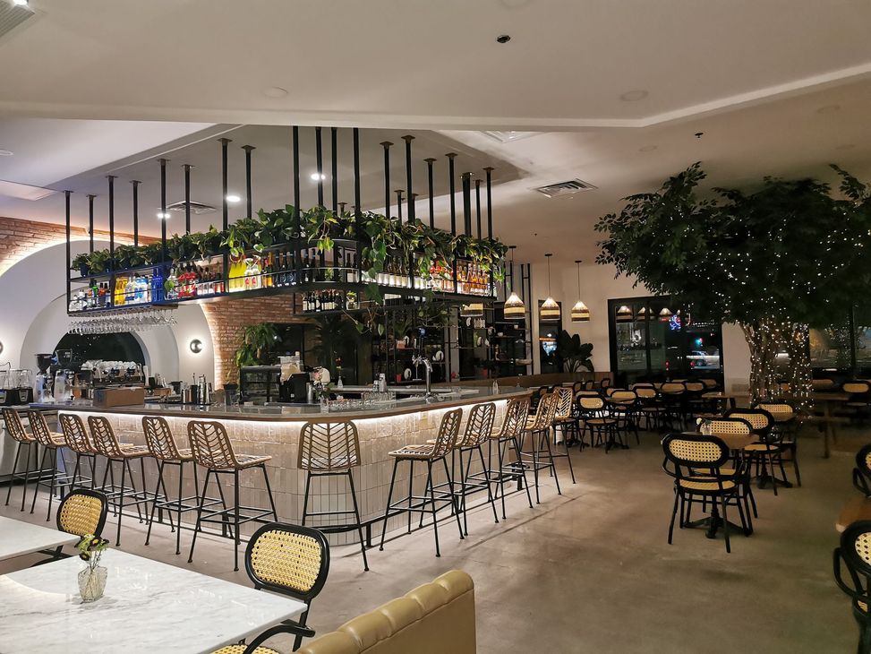 Restaurant et bar élégant en intérieur avec tables vides, tabourets et plantes suspendues