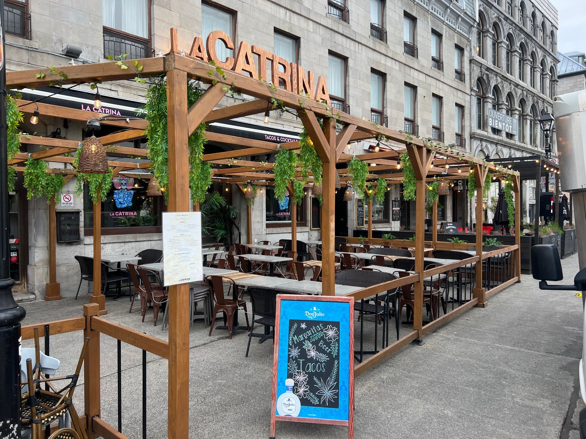 Terrasse extérieure de café avec pergolas en bois et tables vides à l'extérieur d'un restaurant de la ville
