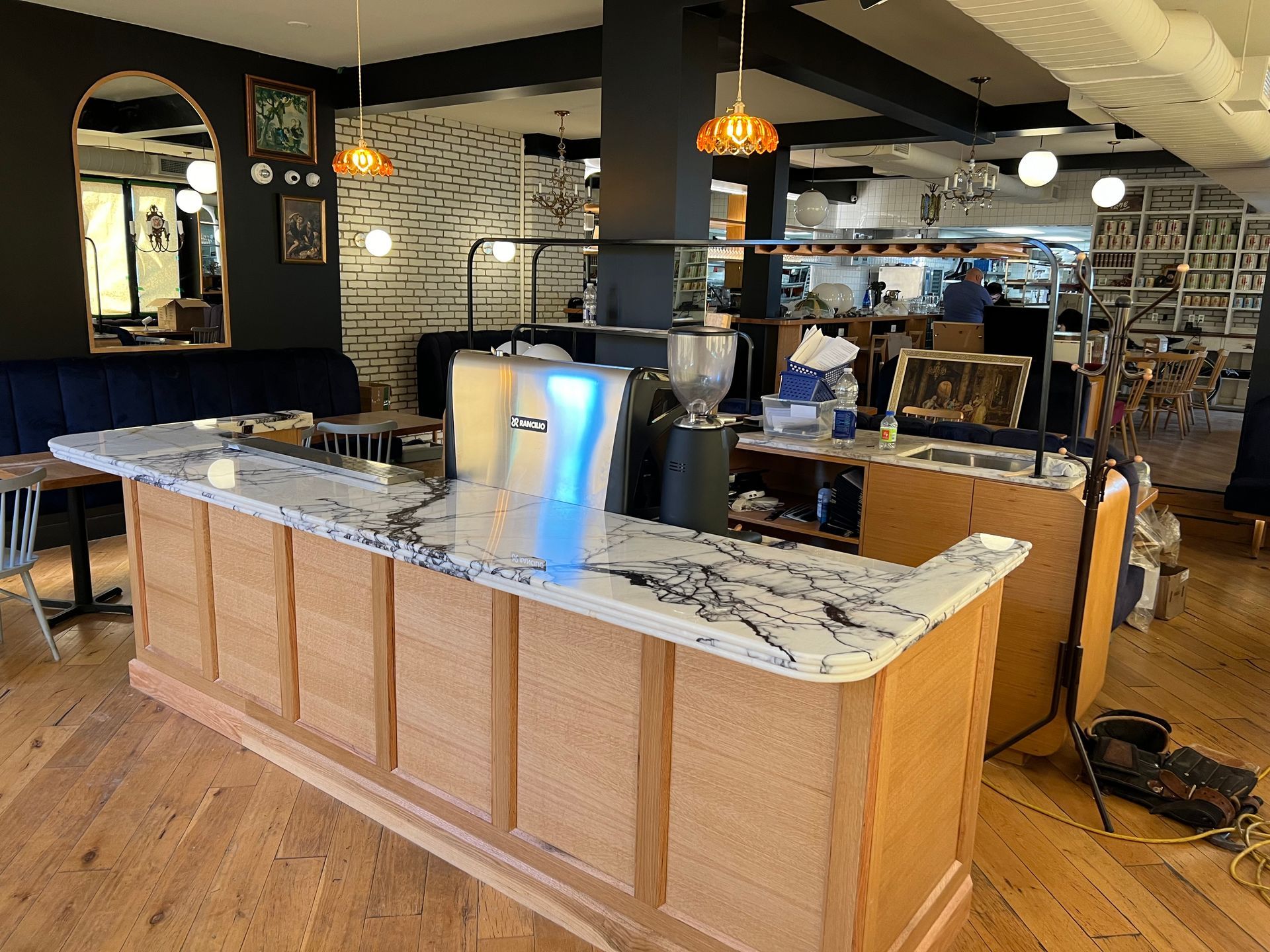 Comptoir de restaurant avec plateau en marbre, tireuses à bière et suspensions lumineuses dans un espace de restauration moderne