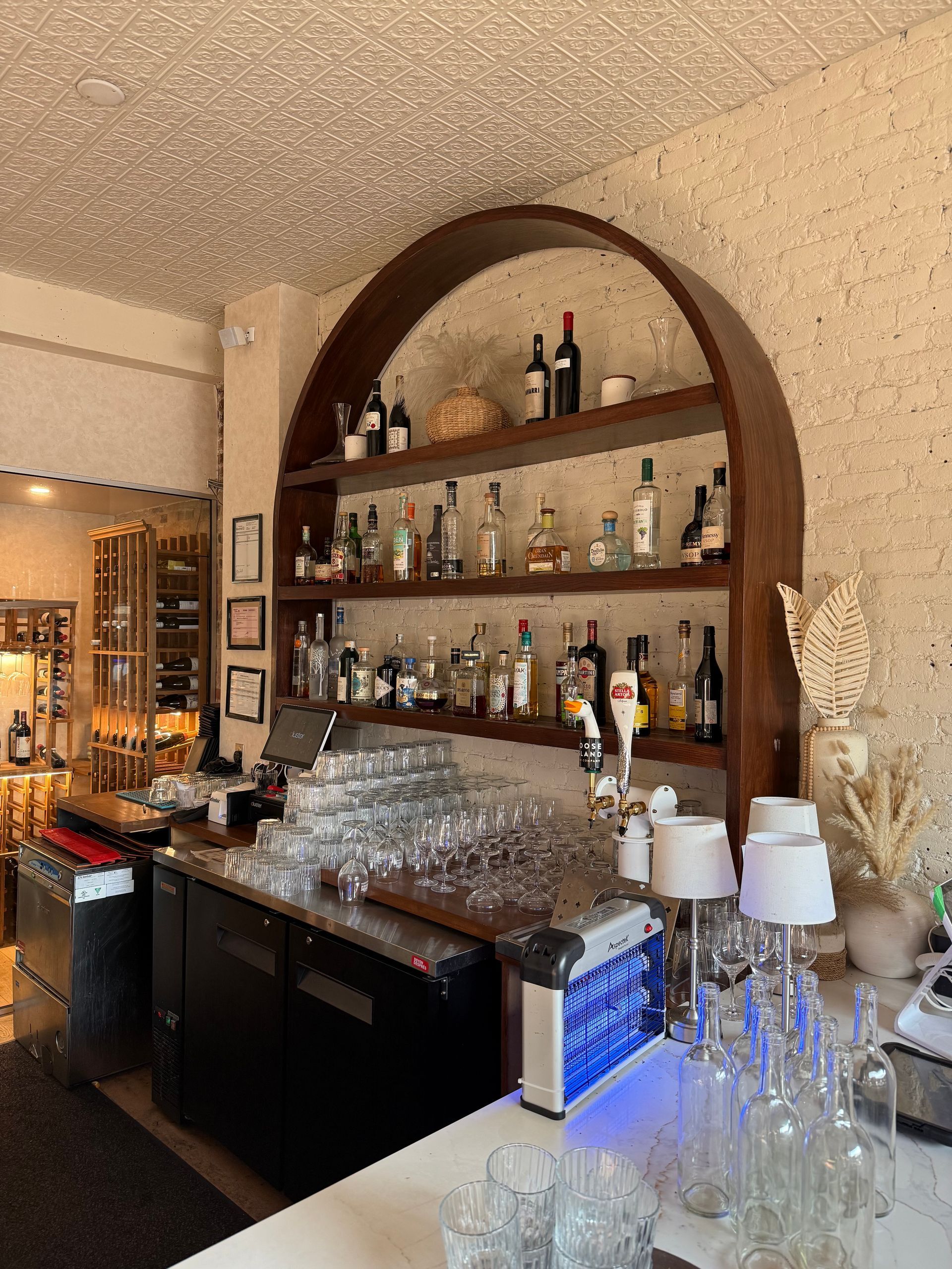 Bar avec étagères de bouteilles d'alcool, de verres et de tireuses à bière sous un éclairage chaleureux