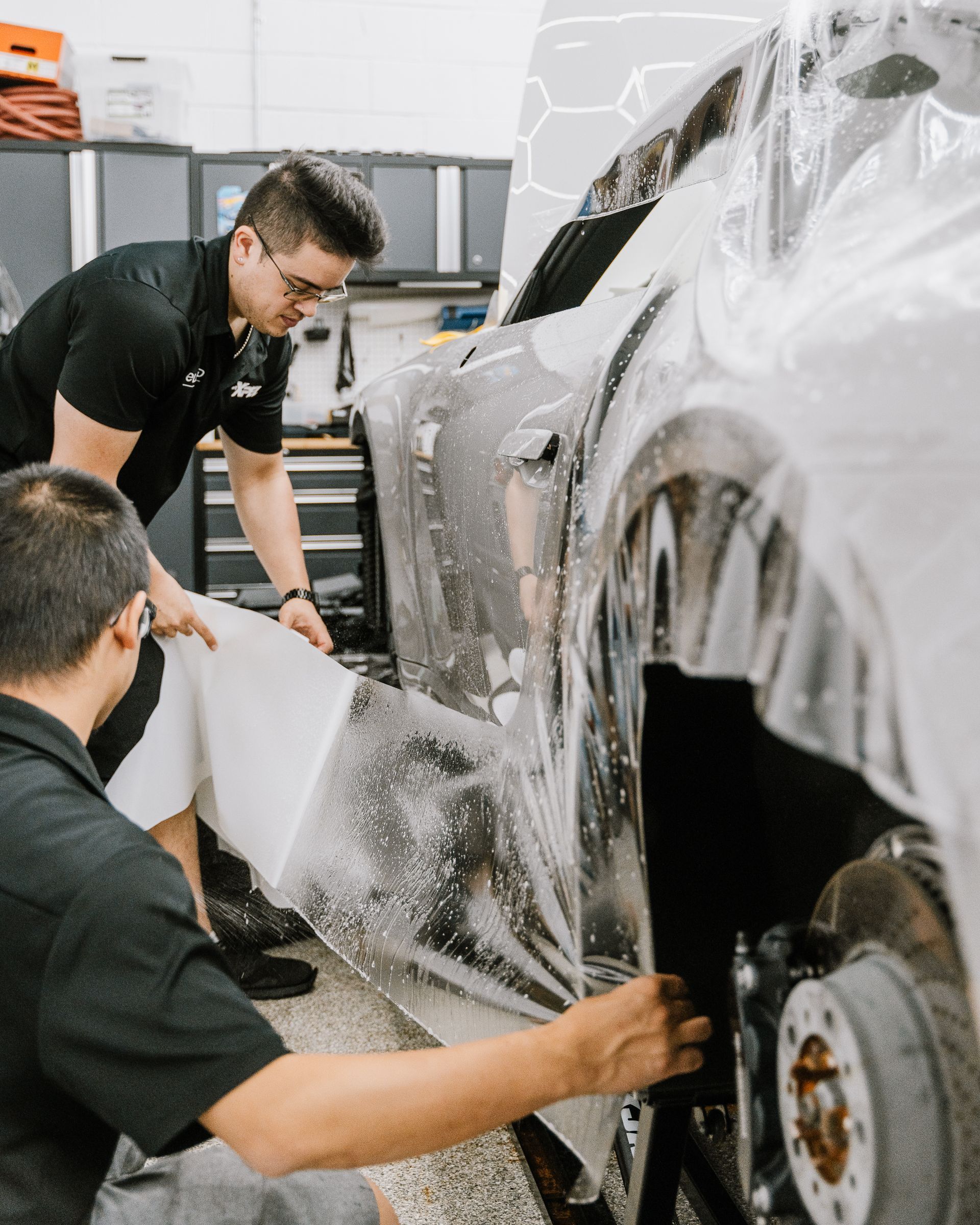 A man is wrapping a car with plastic wrap