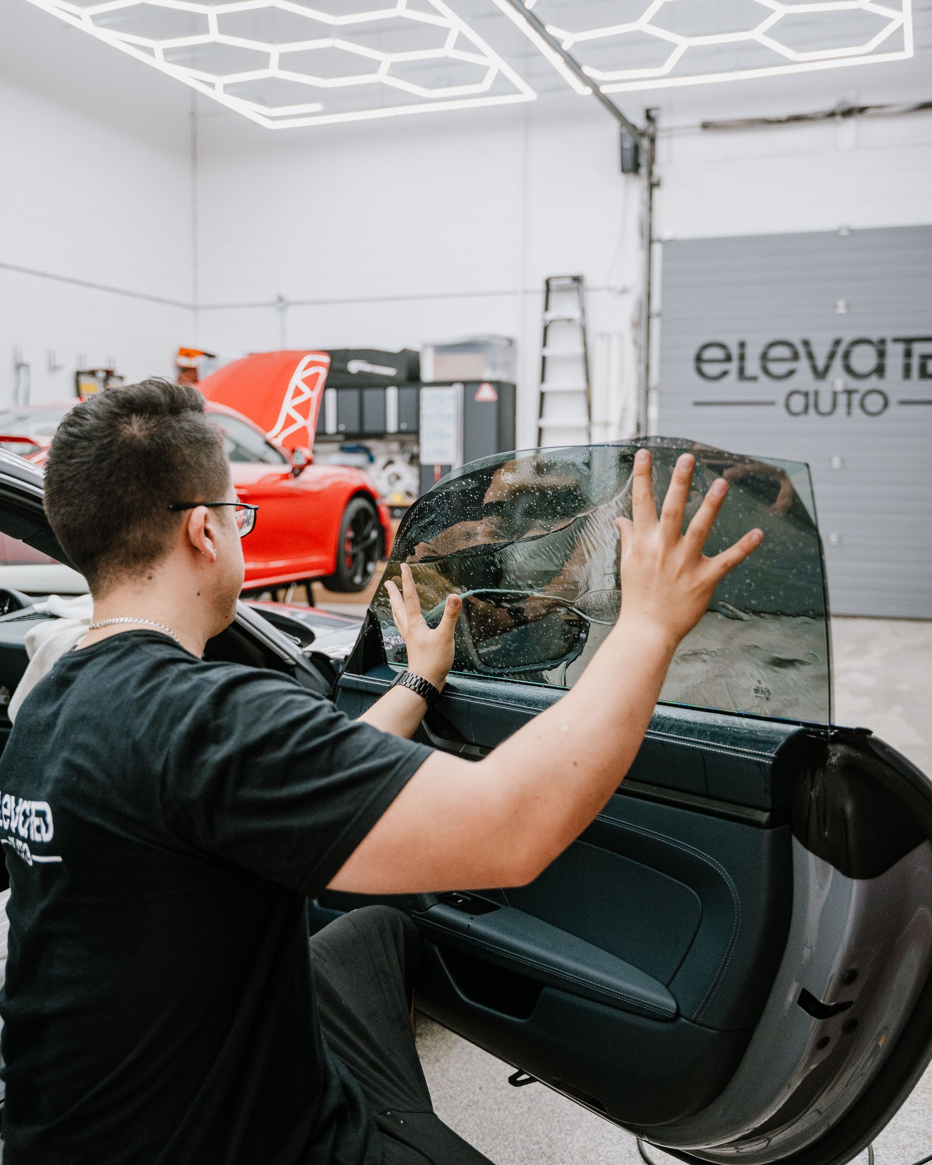 A man is applying window tinting to a car door.