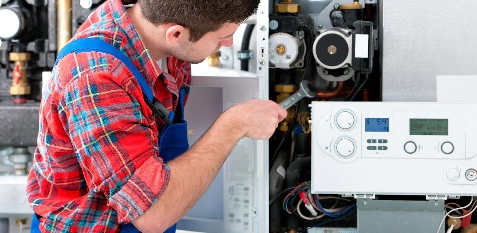 Technician inspecting an open boiler with tools in a utility room
