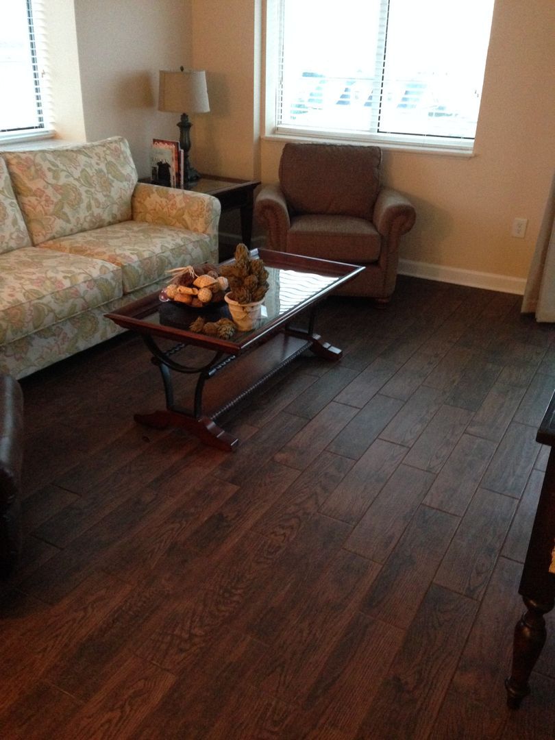 Living room with dark wood flooring, couch, armchair, and coffee table.