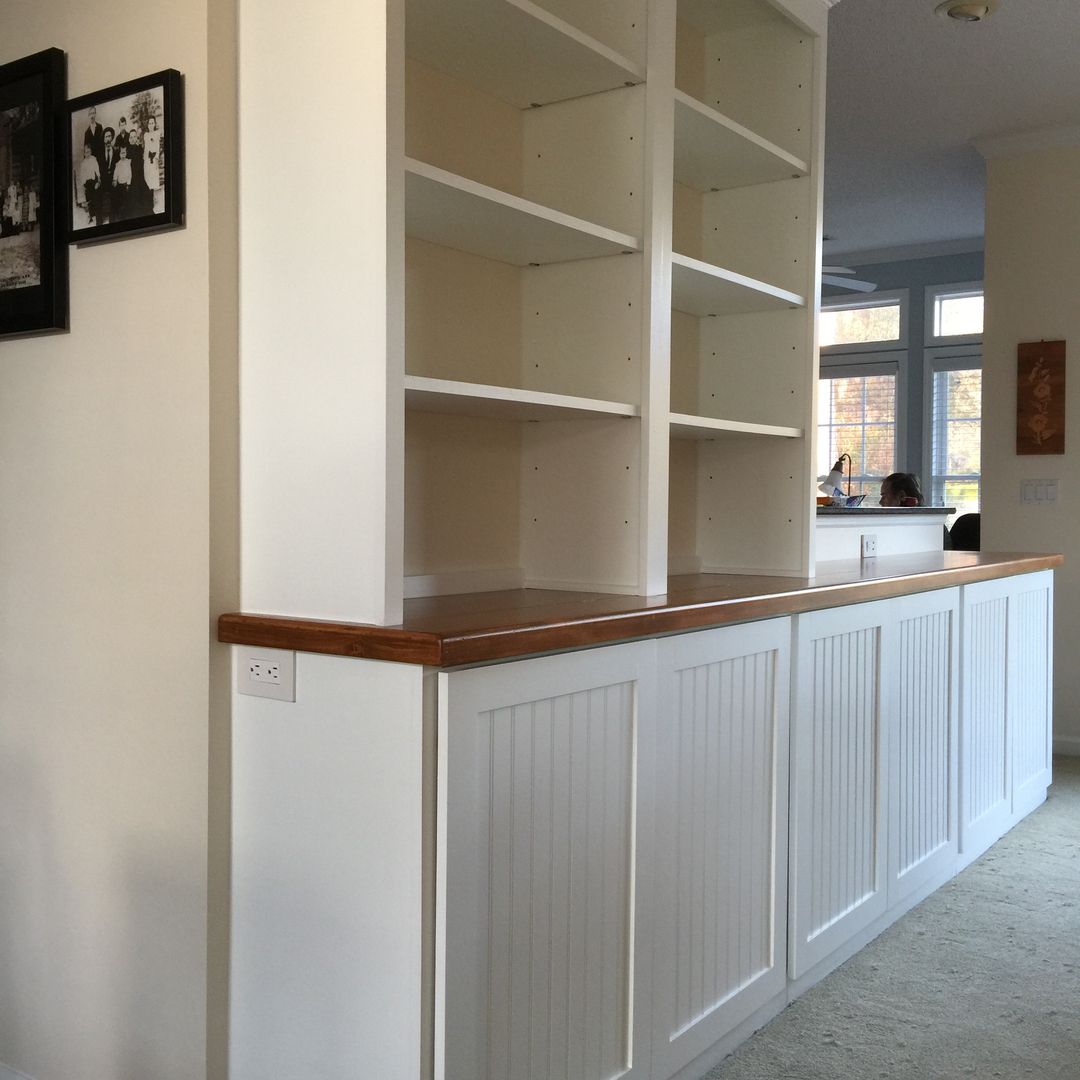 White built-in shelves with wood countertop and beadboard paneling, in a home interior.