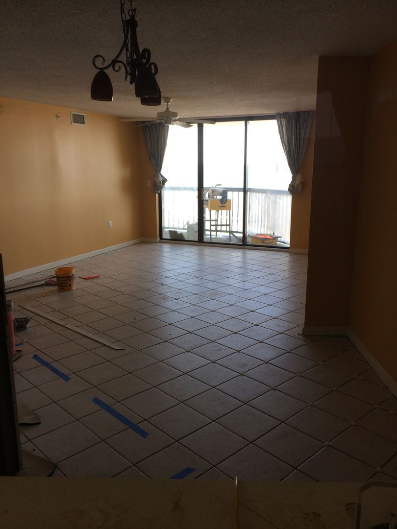 Empty living room with orange walls, tile floor, and a large sliding glass door to a balcony.