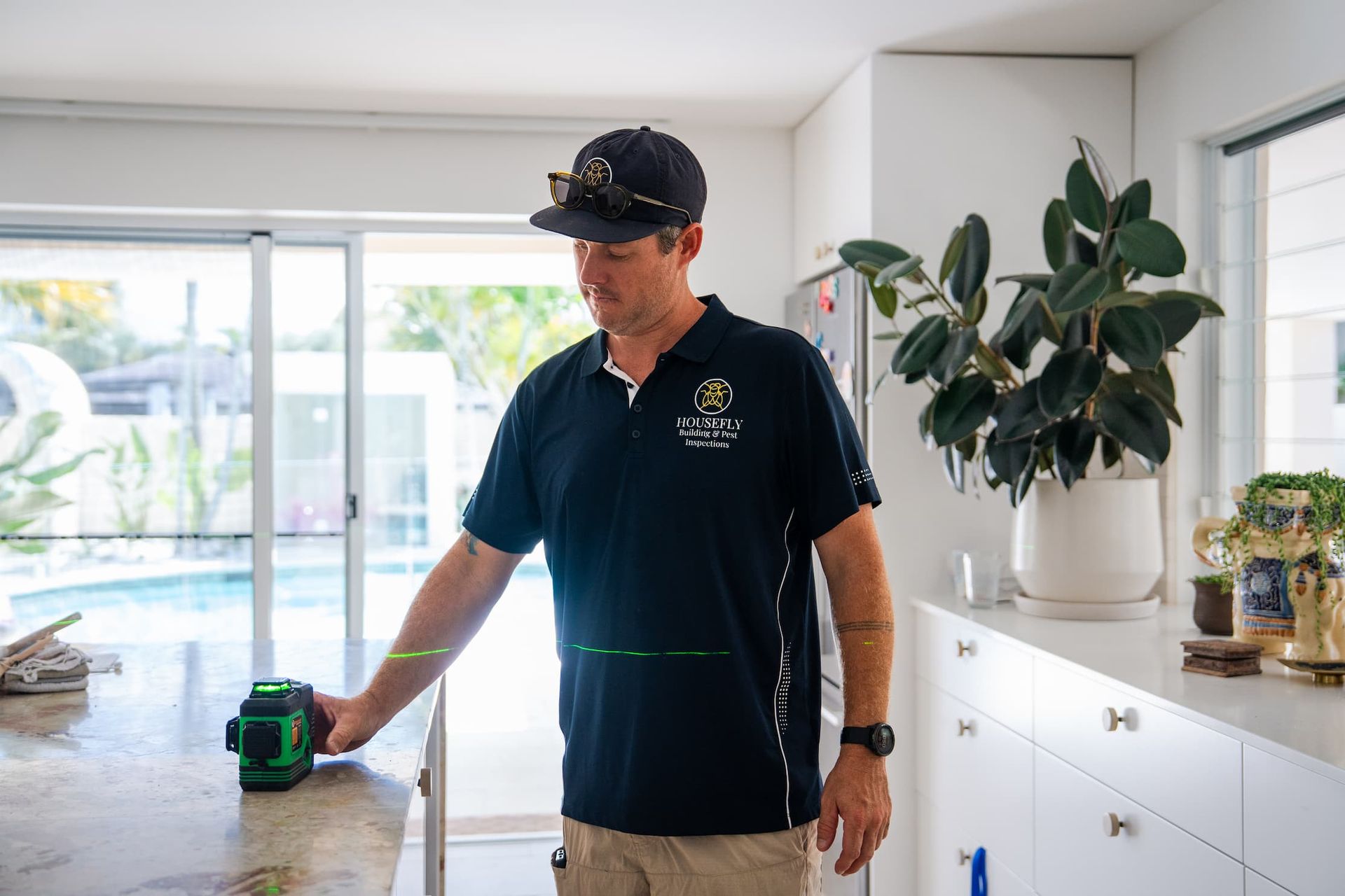 A man is measuring a cabinet with a tape measure in a kitchen.