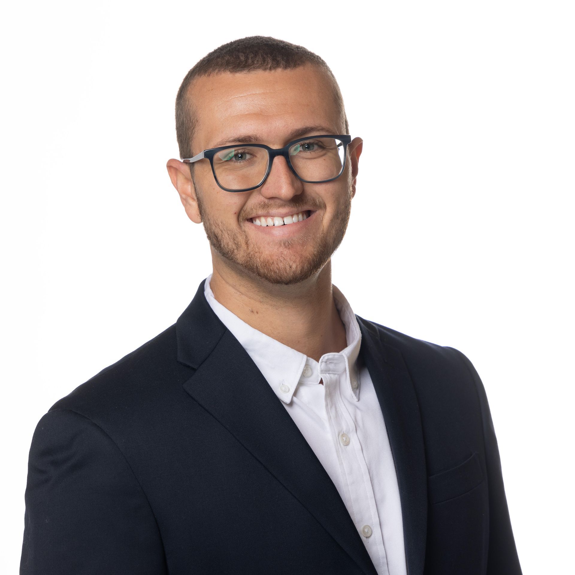 A man wearing glasses and a suit is smiling for the camera.