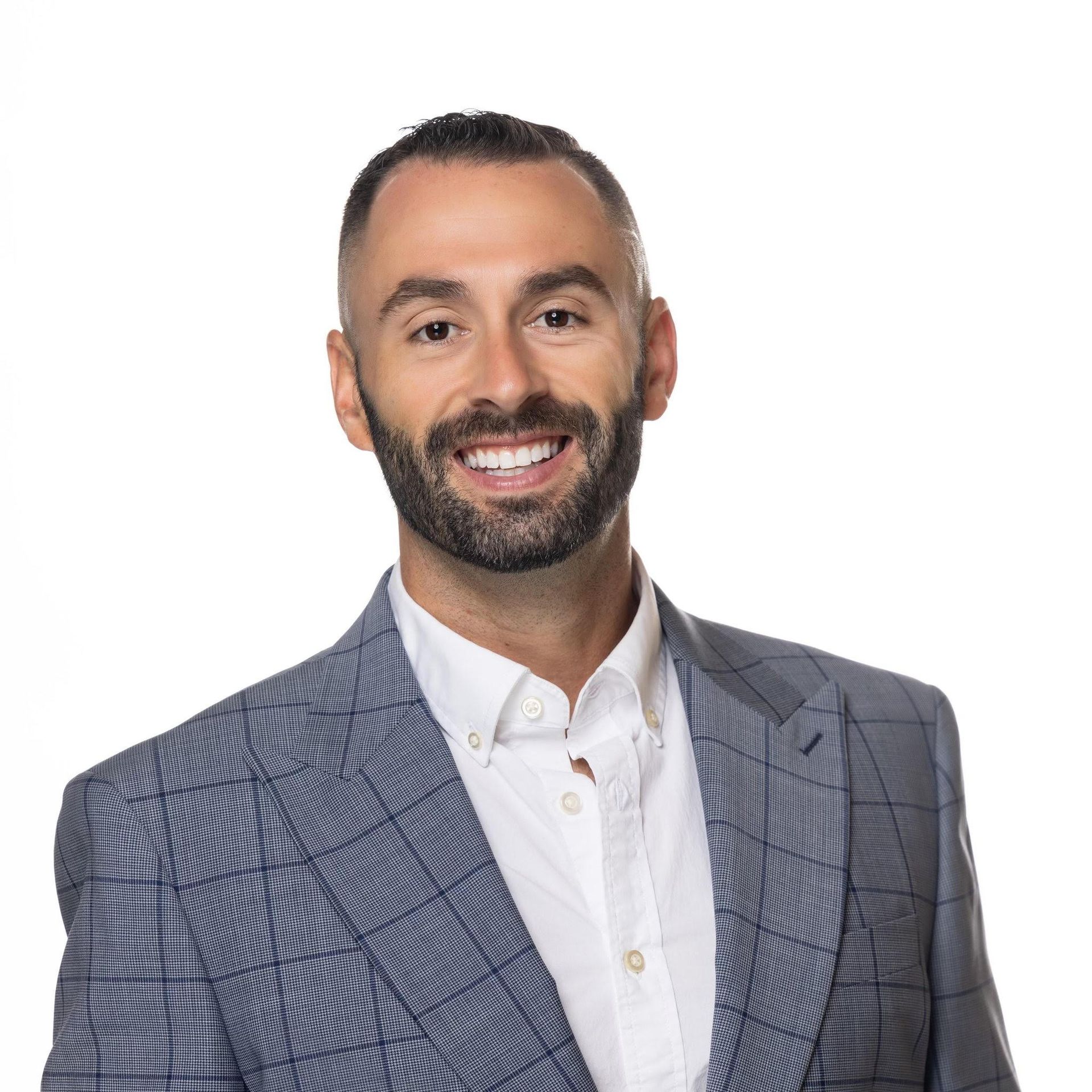 A man with a beard is wearing a suit and smiling.