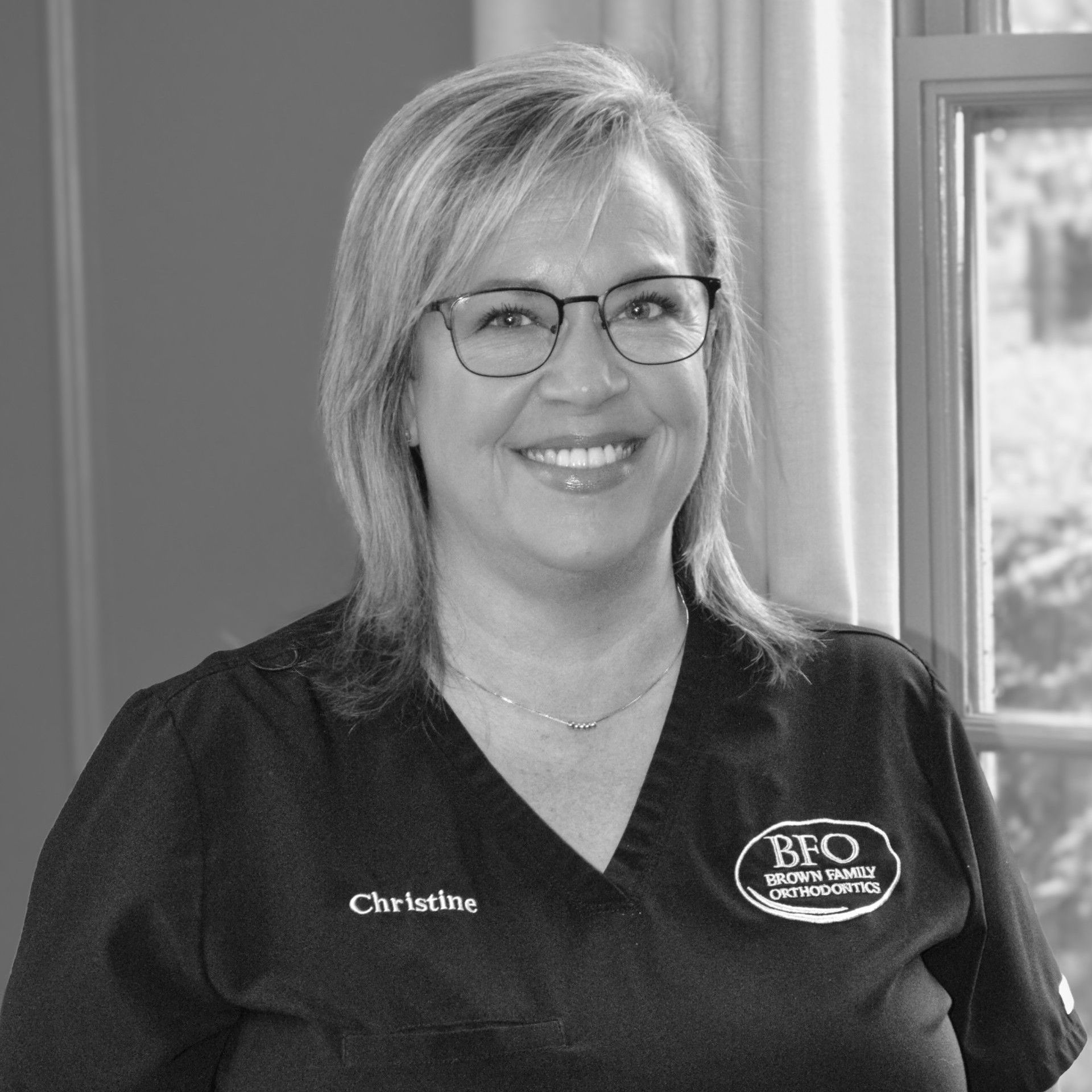 A woman wearing glasses and a black shirt is christine treatment coordinator