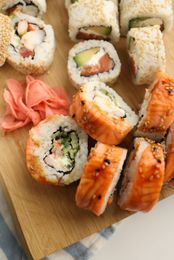 Assorted sushi rolls on a wooden board with pickled ginger and salmon nigiri