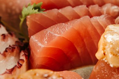Close-up of sliced salmon sashimi with seared octopus and garnish on a plate