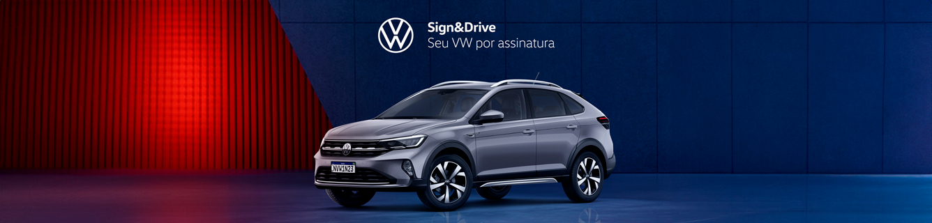 Um Volkswagen Tiguan prateado está estacionado em frente a uma parede azul.