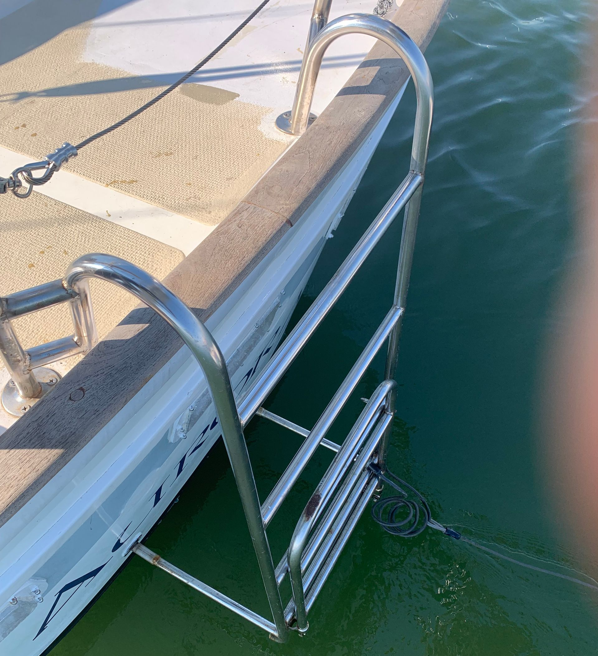 Stainless steel boat ladder extending into water from the side of a boat.