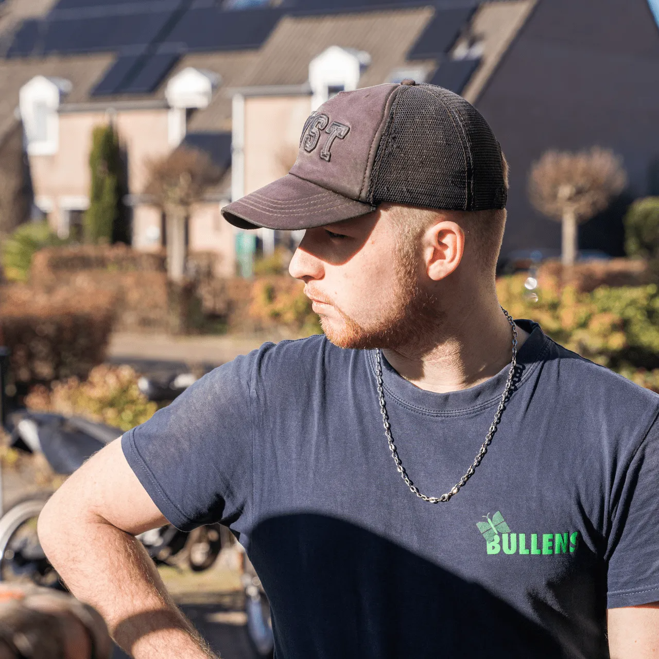 Een weelderige tuin met een centrale, lange en smalle waterpartij, rozenstruiken, bomen en een betegeld terras.