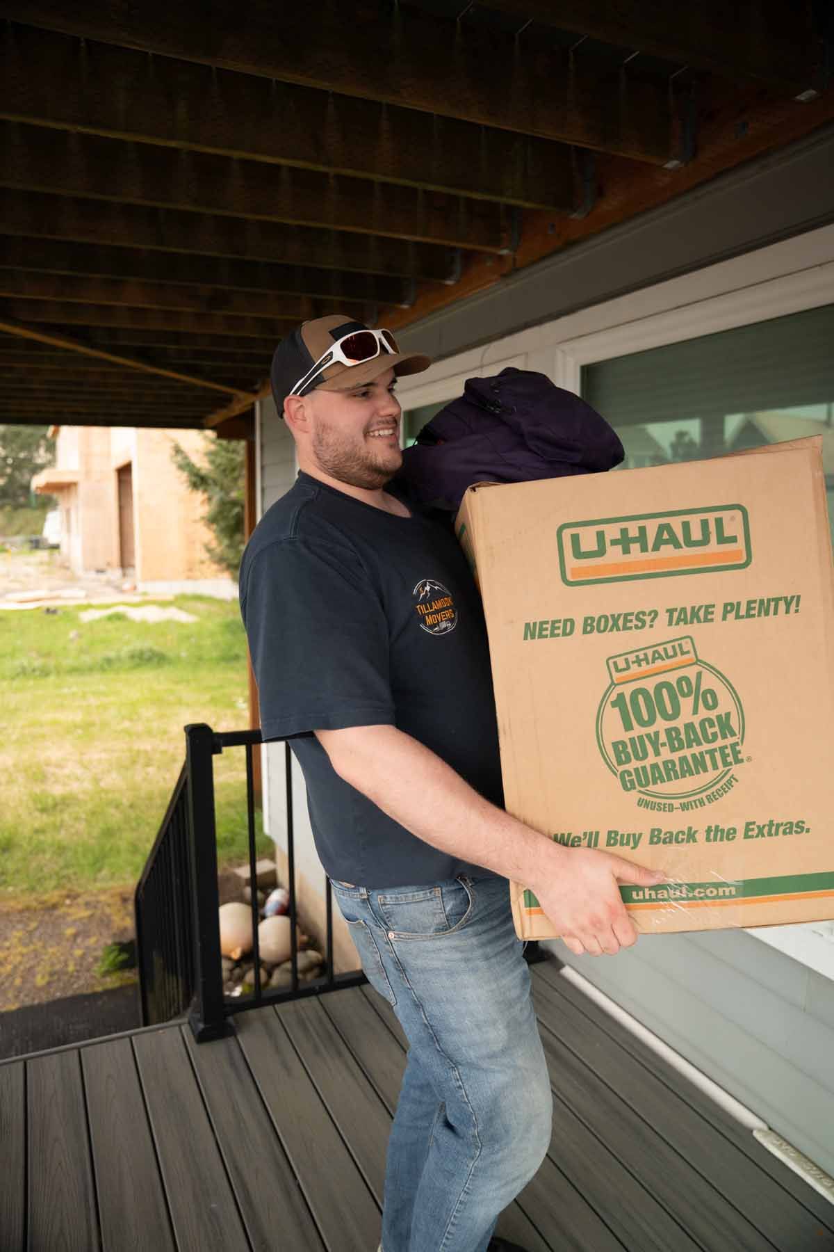 A man is carrying a cardboard box on a porch.