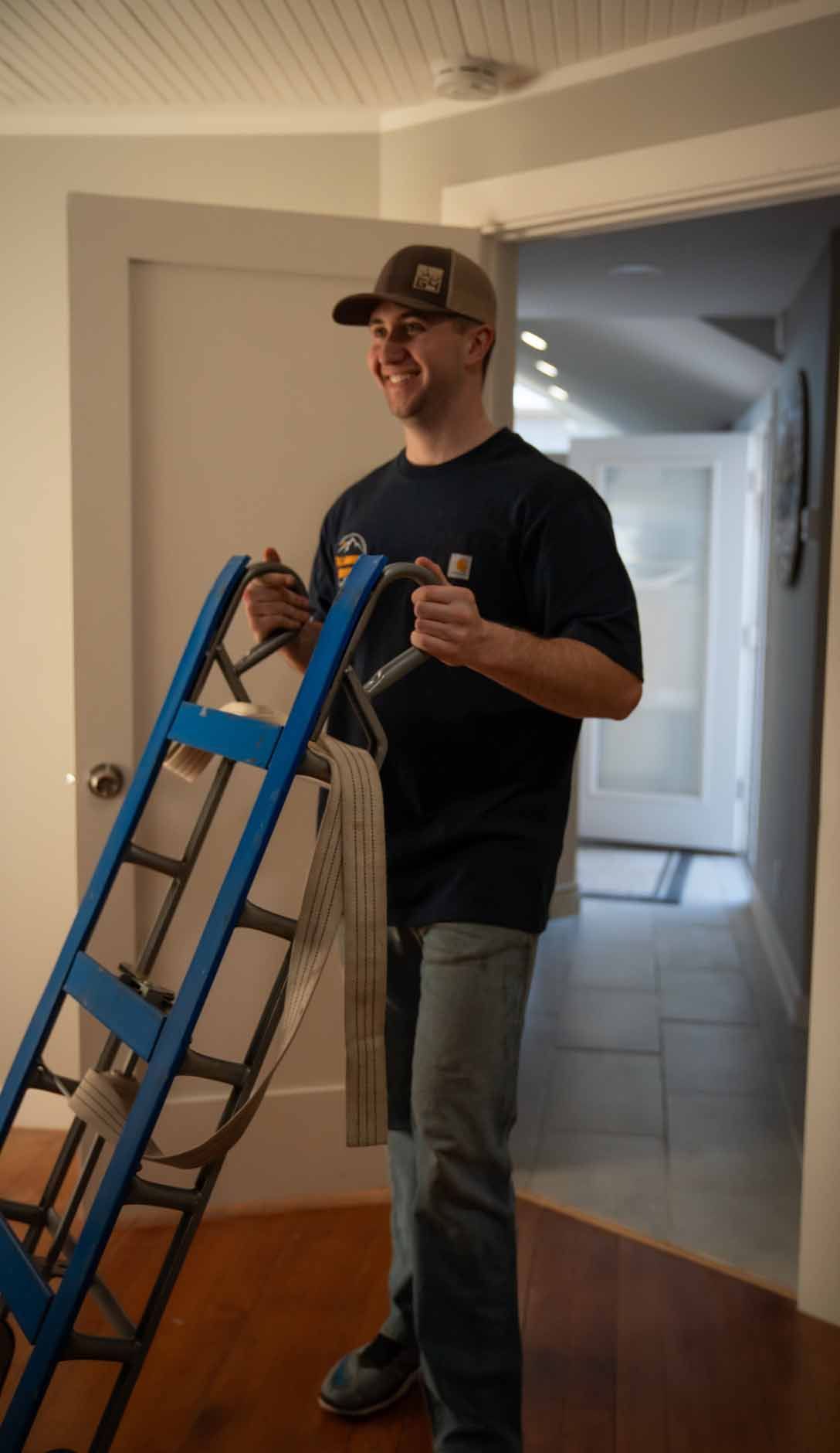 A man is standing next to a blue ladder in a hallway.