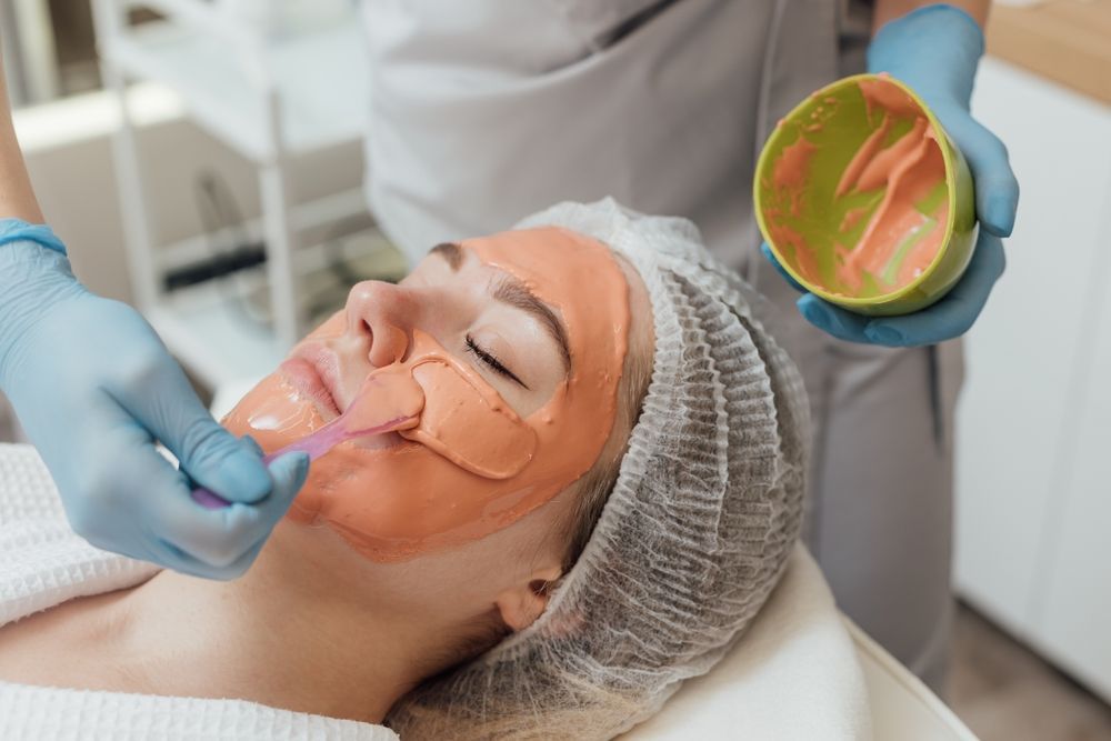 A person wearing protective goggles receives laser skin treatment on their upper lip from a technician in pink gloves.