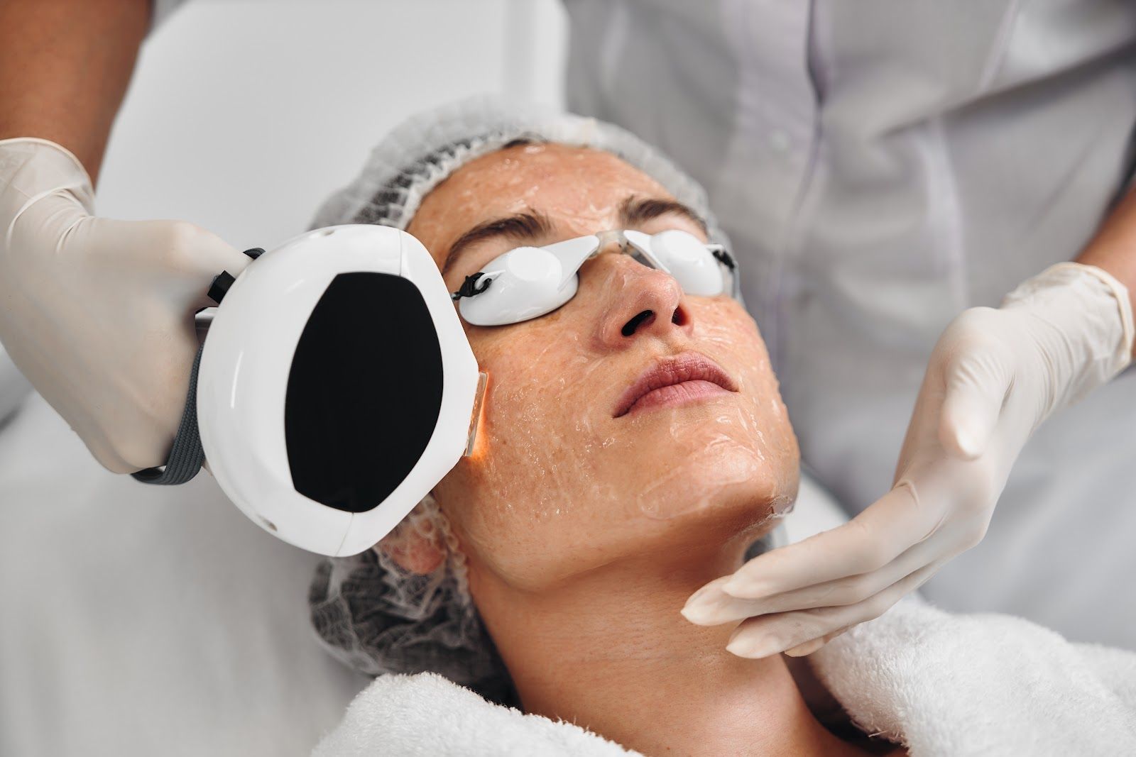 Cosmetic facial treatment with a handheld device applied to a client's face in a spa setting