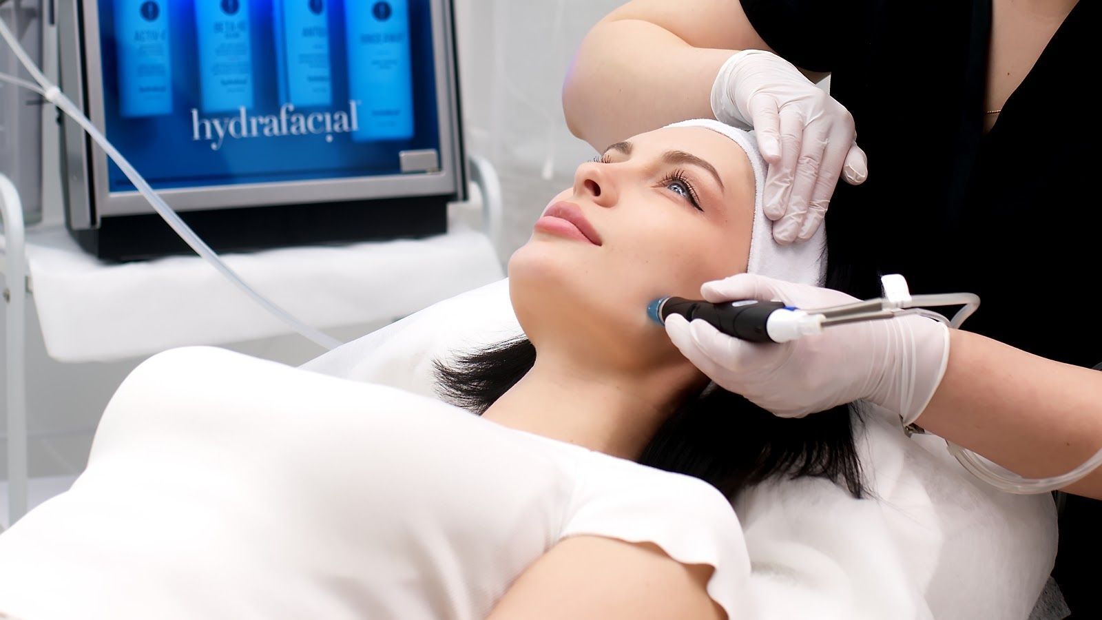 Facial treatment in a spa, with a clinician applying a device to a reclining client’s face