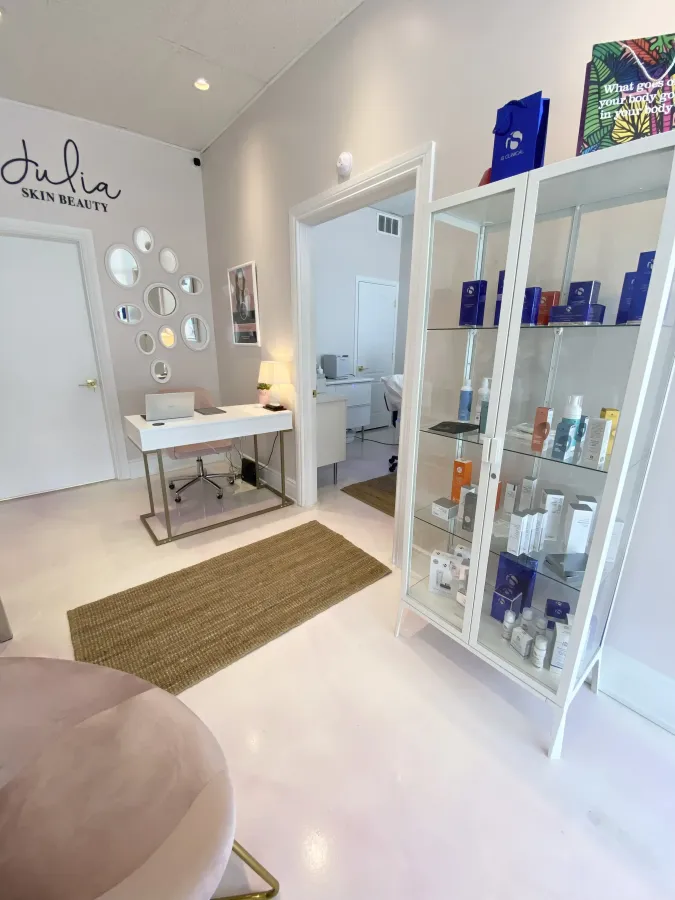 A room with a desk and a display case filled with cosmetics.
