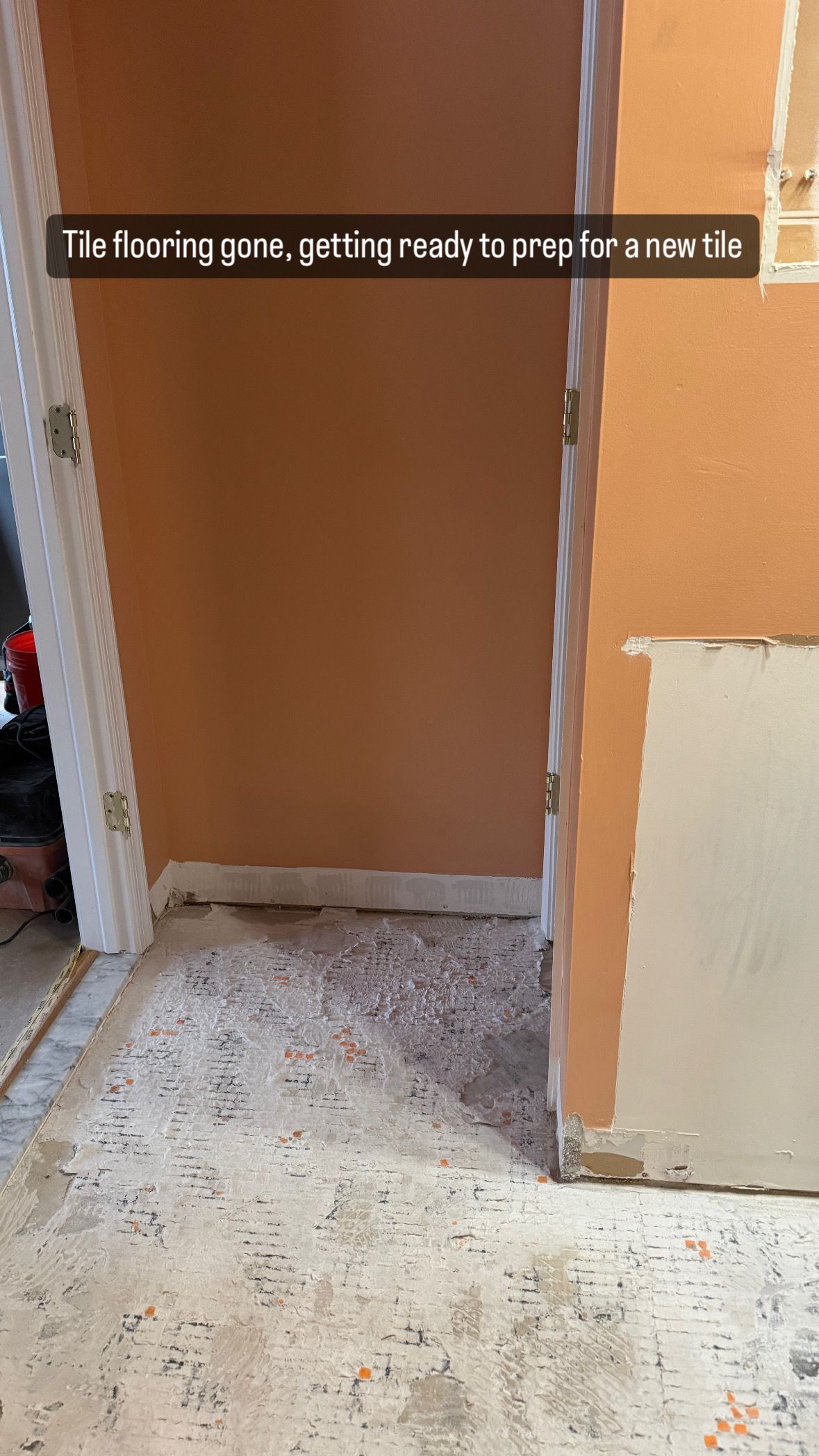 Room interior with peach-colored walls, doorway, and floor covered with debris.