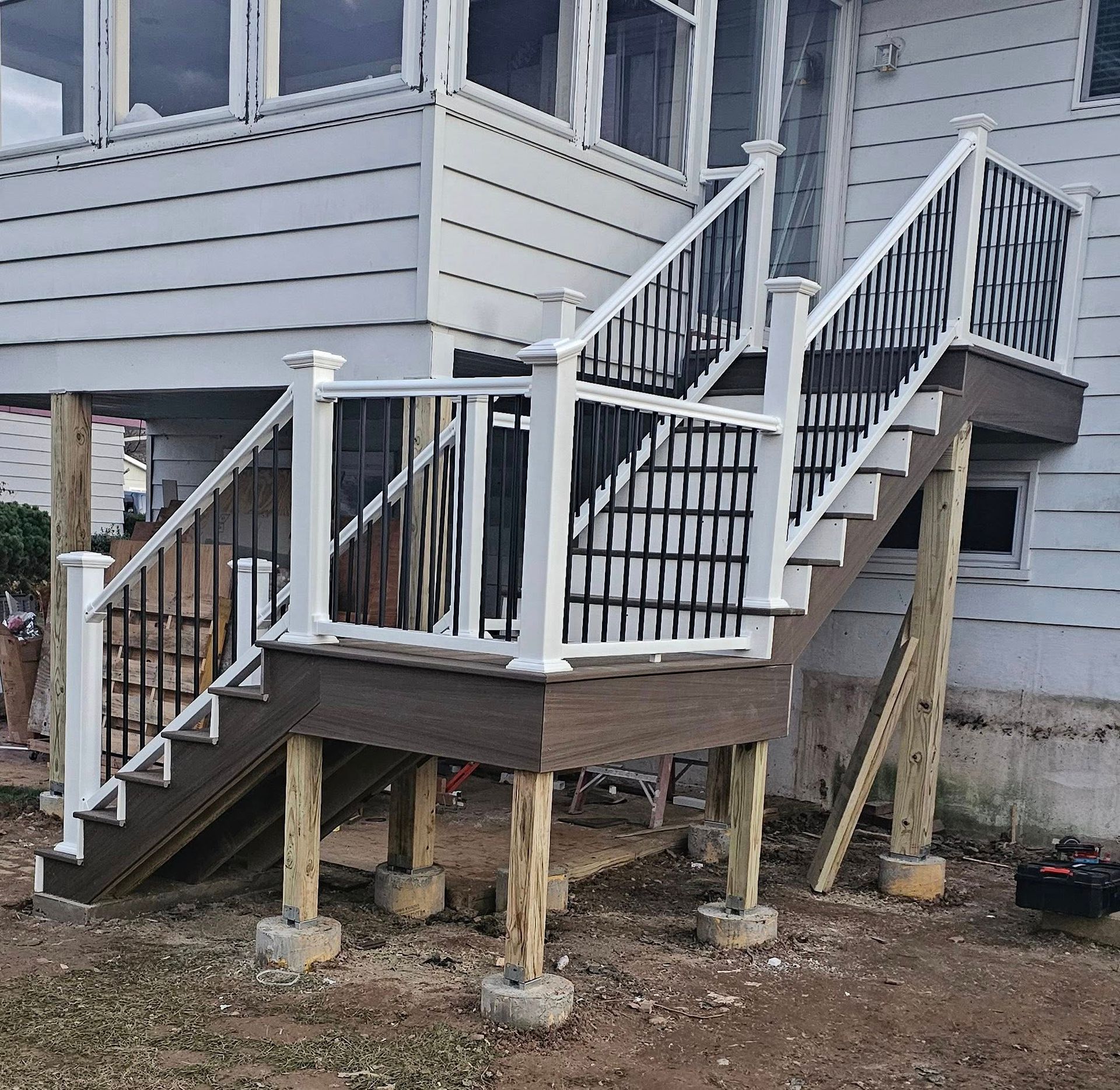 Outdoor deck and stairs with white railing, black spindles, and composite decking.