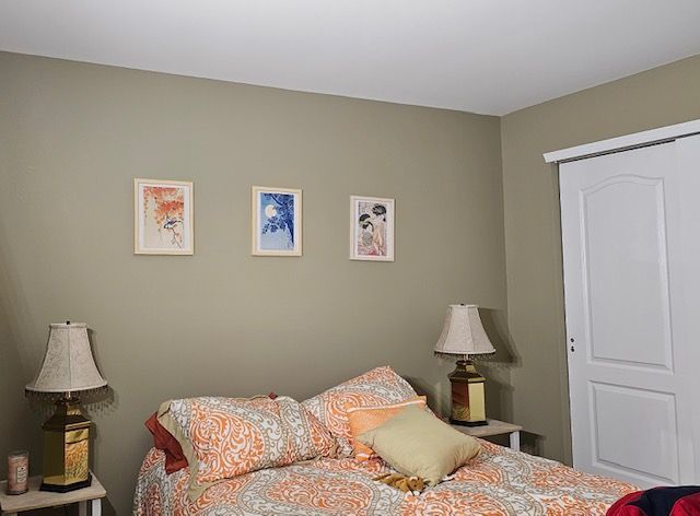 Bedroom with bed, art, bedside tables, lamps, and a white sliding door. Beige walls.