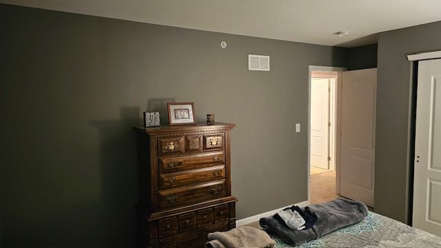 Bedroom with dark gray walls, wooden dresser, open door, bed with blanket.