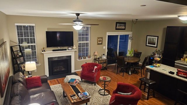 Living room with fireplace, TV, red armchairs, dark brown couch, and dining table.