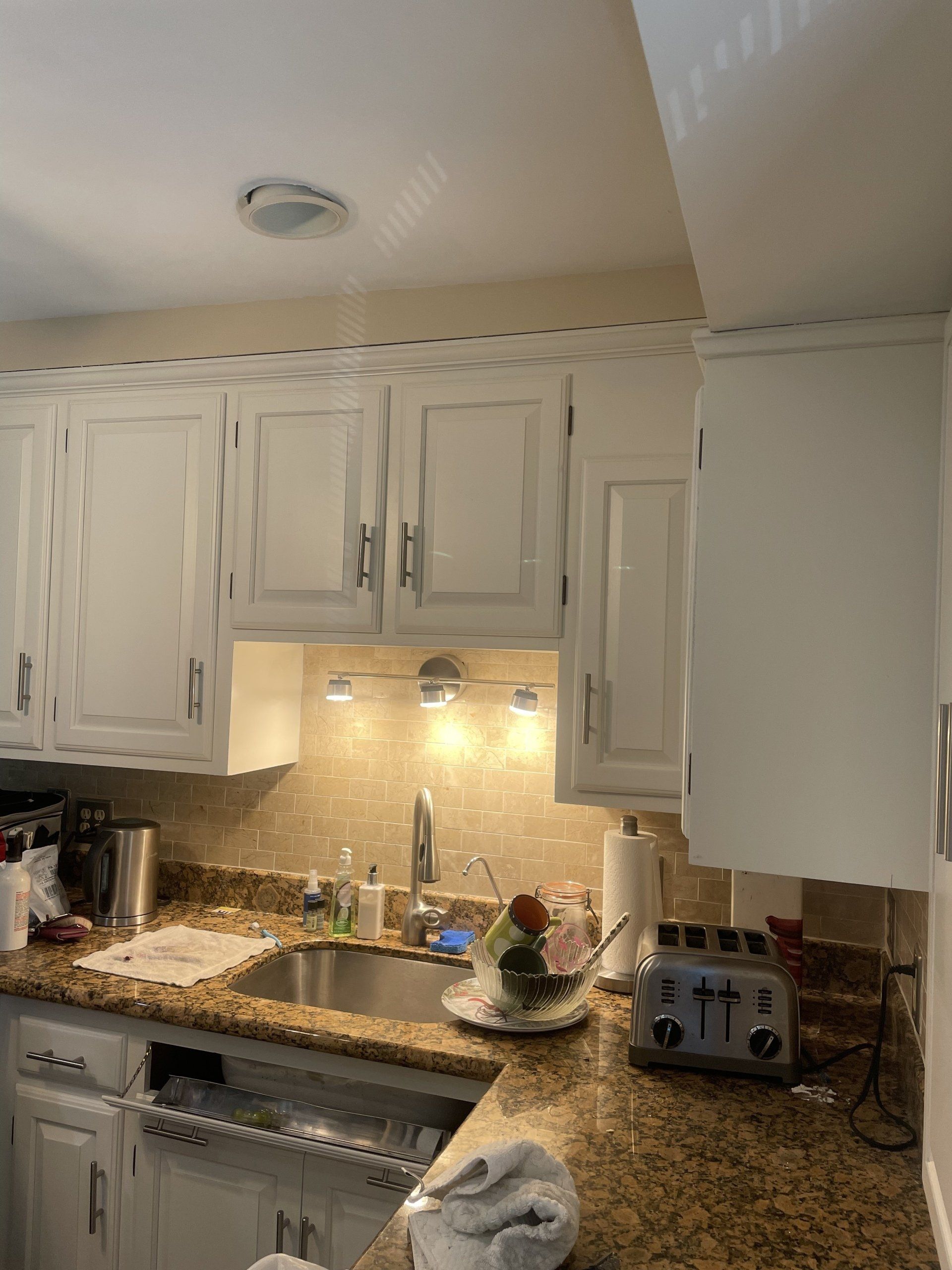 Kitchen with white cabinets, stainless steel sink, granite countertop, and toaster.