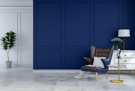 Blue accent wall with chair, white chest, and potted plant.