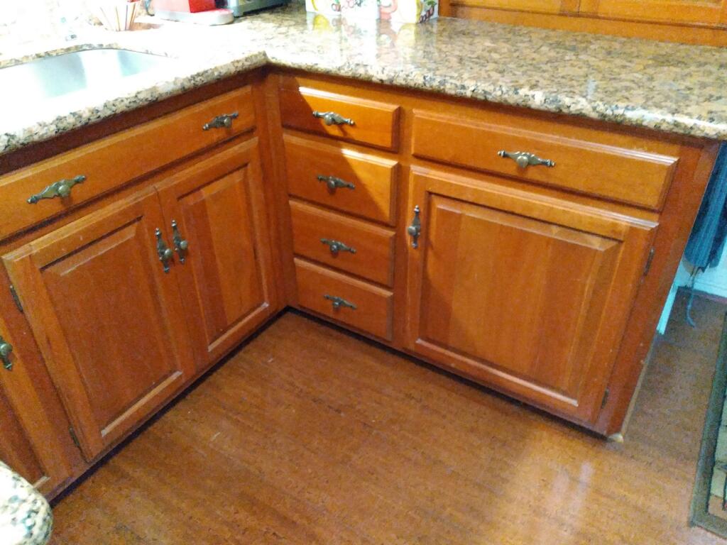 Wooden kitchen cabinets with granite countertop. Brass hardware. Hardwood floor.