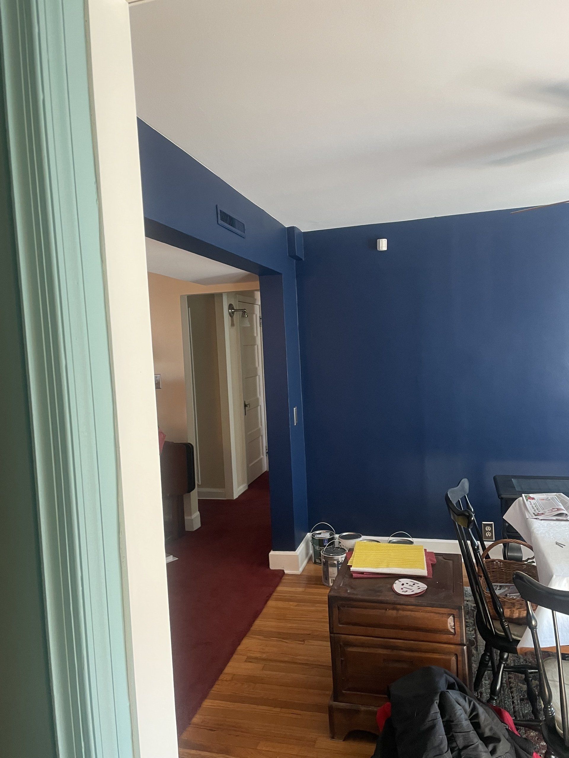 Blue-painted wall with a doorway leading to a hallway with a red floor.