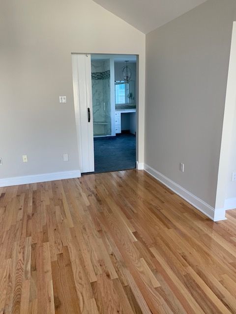 Hardwood floor with a view of a bathroom through an open doorway and a white sliding door.
