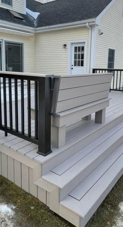 A composite deck with steps, railing, and built-in planter bench. Exterior view of a light-colored home.
