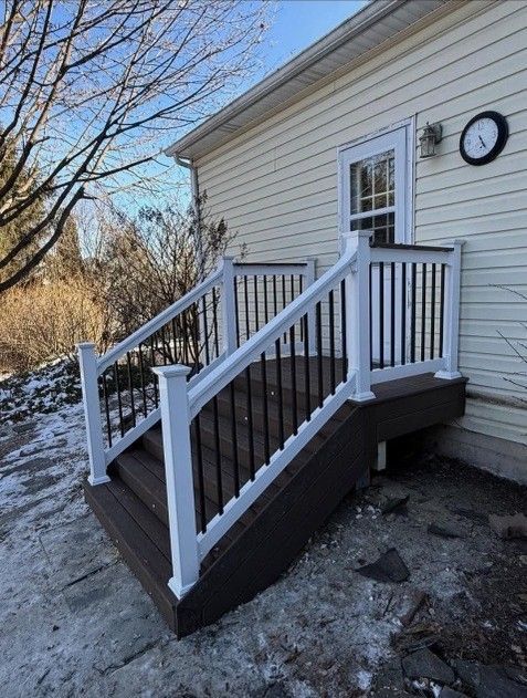 Brown deck with white railing and black spindles, leading to a cream-colored house.