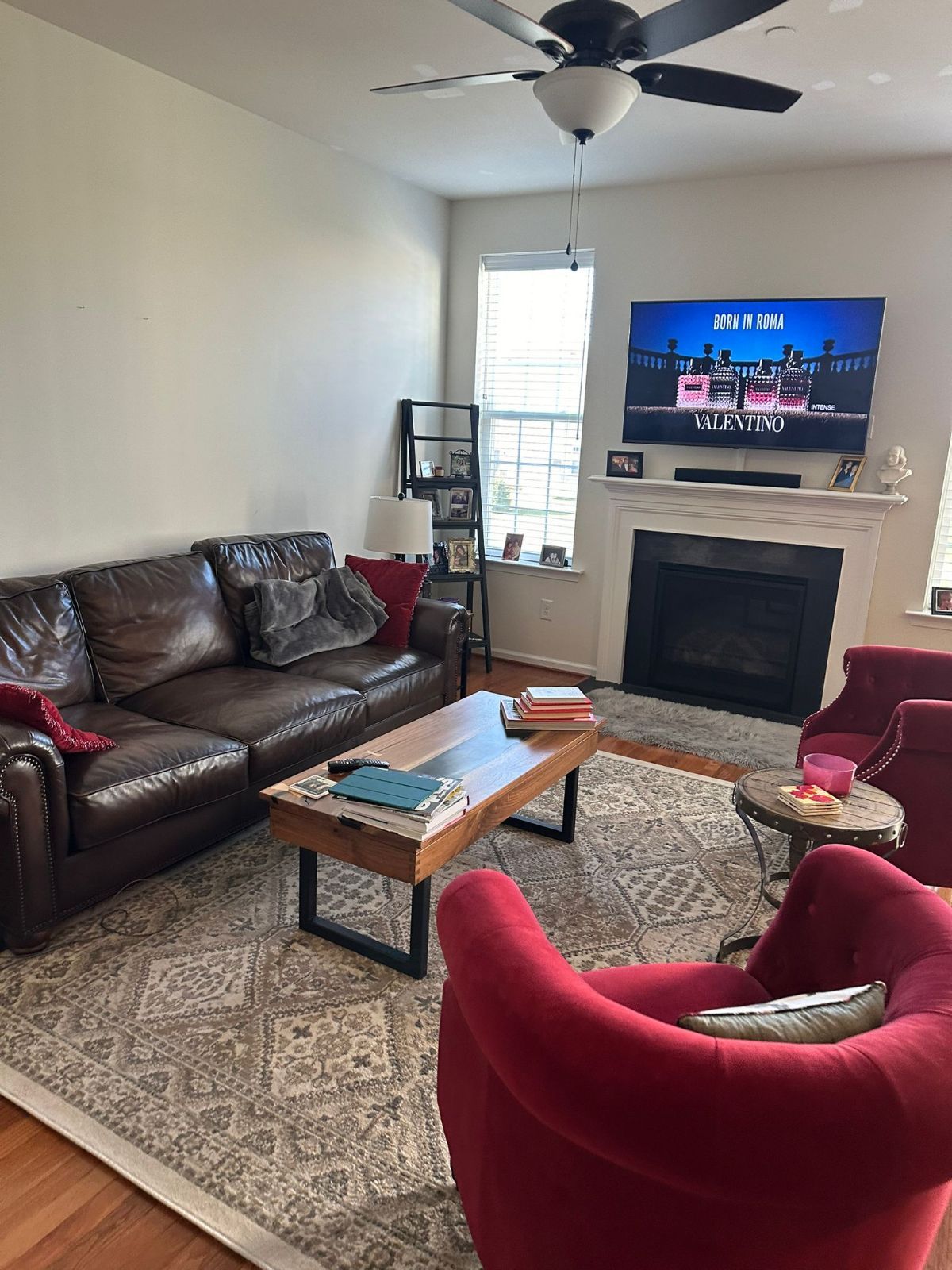 Living room with leather sofa, red chairs, fireplace, TV, rug, coffee table.