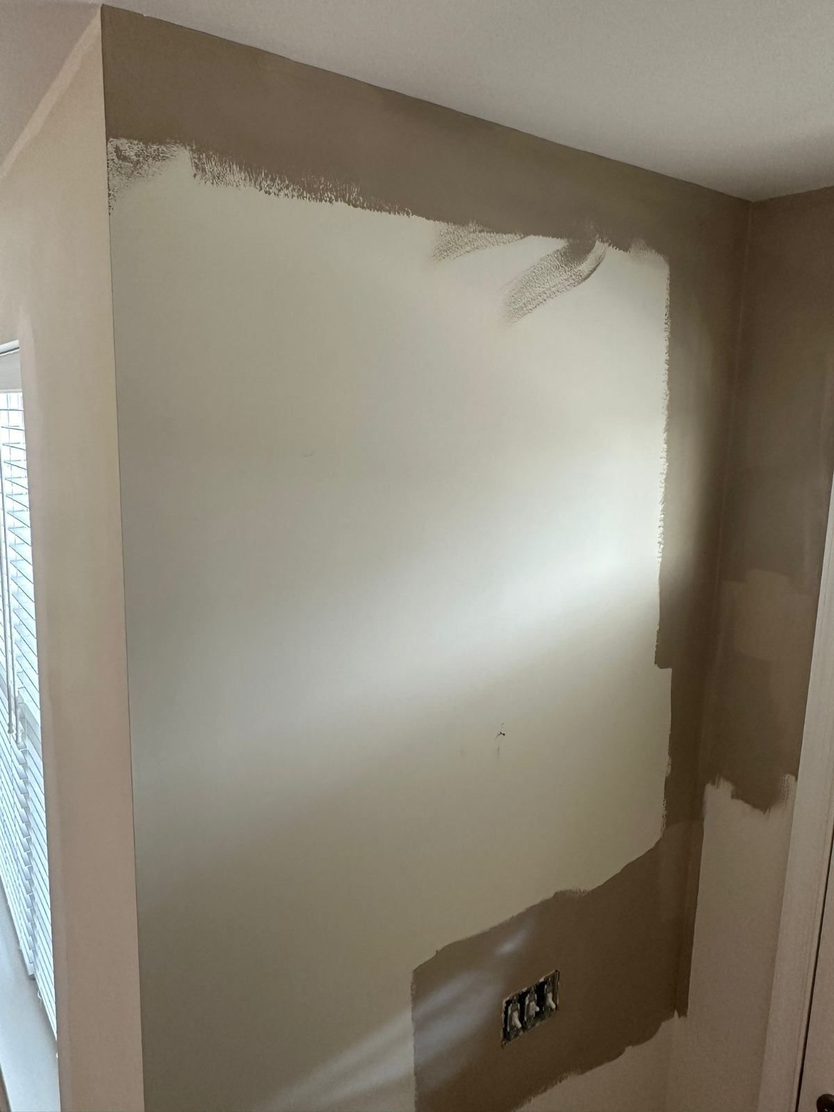 Beige wall partially painted in a lighter color, with electrical outlets visible.