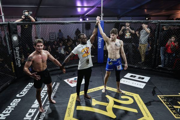 Three men are standing in a boxing ring holding hands.