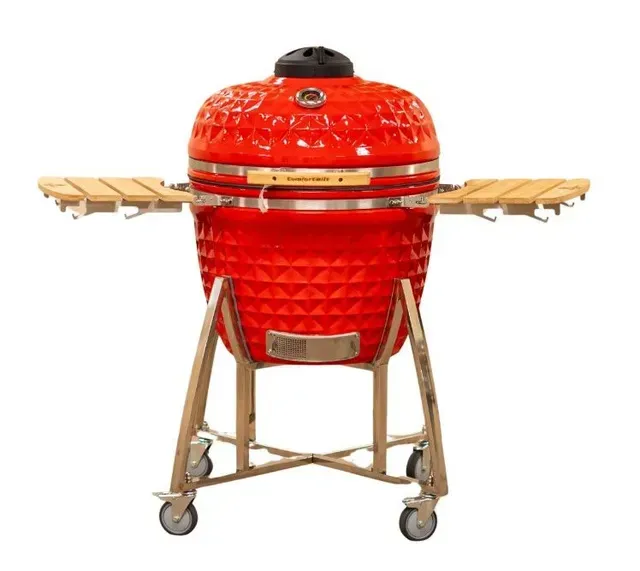 Red ceramic kamado grill on a wheeled stand with side shelves, isolated on white background