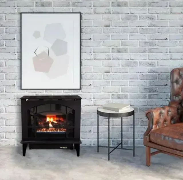 Cozy living room with lit fireplace, framed art, side table, and brown leather chair against white brick wall