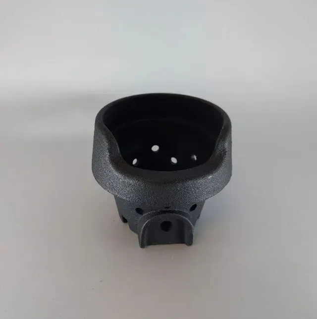 Black plastic cup-shaped part with a perforated base on a light gray background