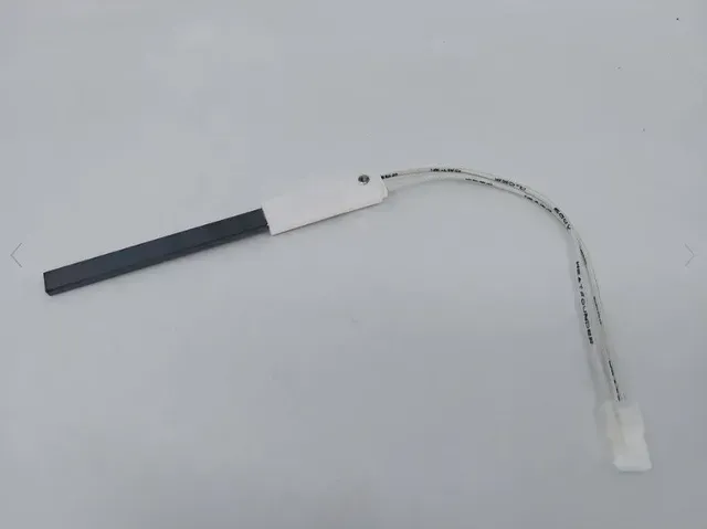 Black rectangular sensor with a white cable and connector on a light background