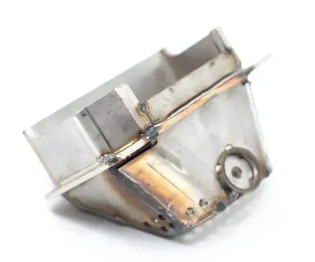 Small silver metal part with welded seams and a circular fastener on the side