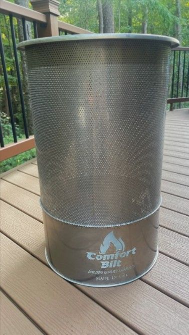 Metal mesh fire pit on a wooden deck with a forested background