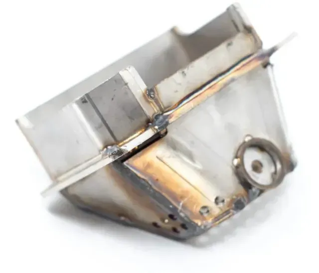 Worn metal box with welded seams and a round port, shown at an angle on a white background