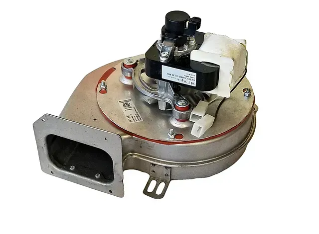 Small metal mechanical component with a circular silver body, black valve assembly, and rectangular opening on the front.